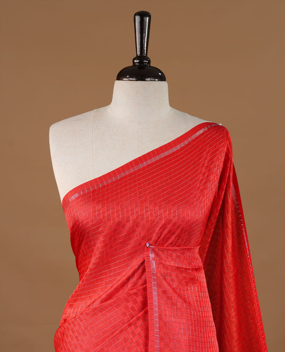 Red colour Semi Tussar saree featuring an elegant zari fancy check pattern on the body, highlighted with a small border for a refined look. Comes without a blouse piece.