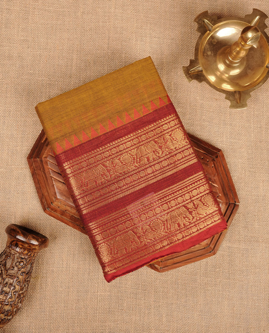 Mustard colour chettinad cotton saree featuring plain body, paired with a black colour traditional gold zari border paired with matching blouse.