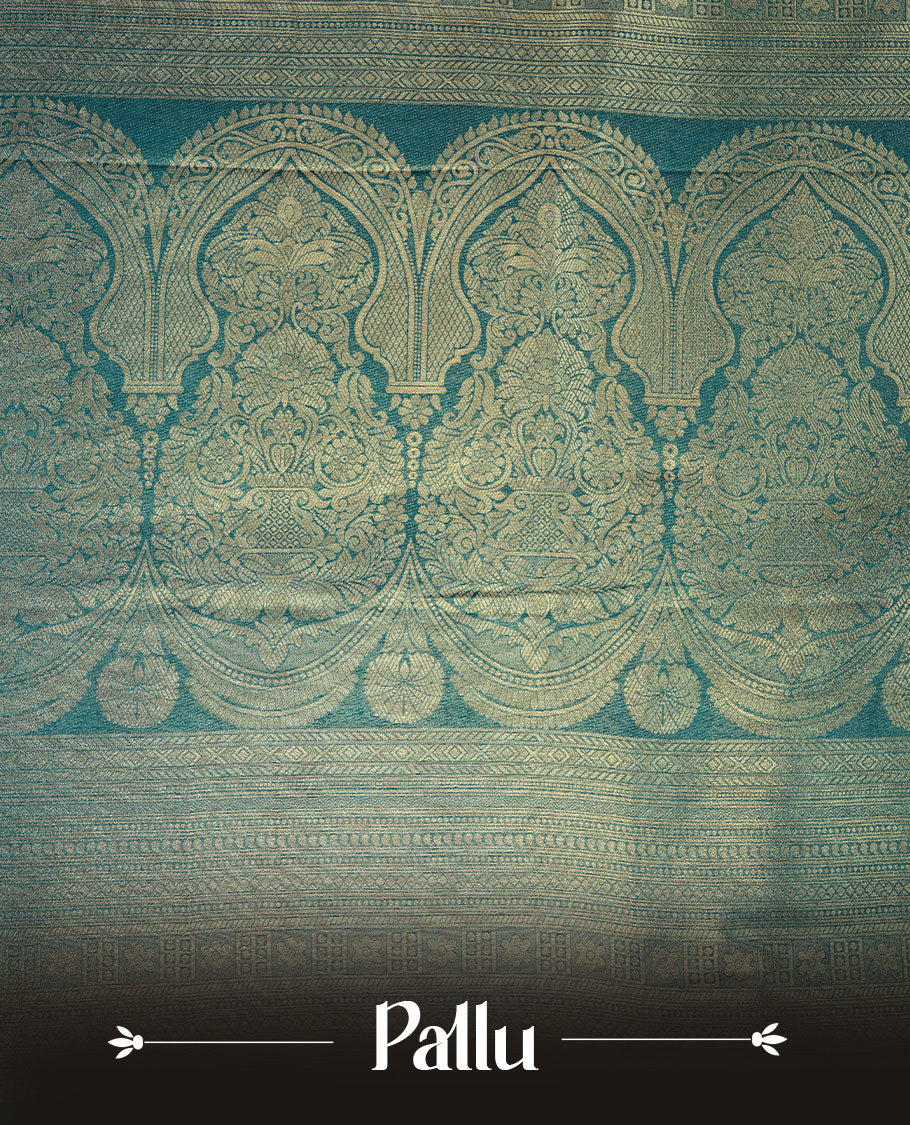 Peacock blue colour semi soft silk brocade saree featuring elegant gold zari floral and paisley motifs across the body, finished with a richly woven self-colour border and pallu, paired with a matching blouse.