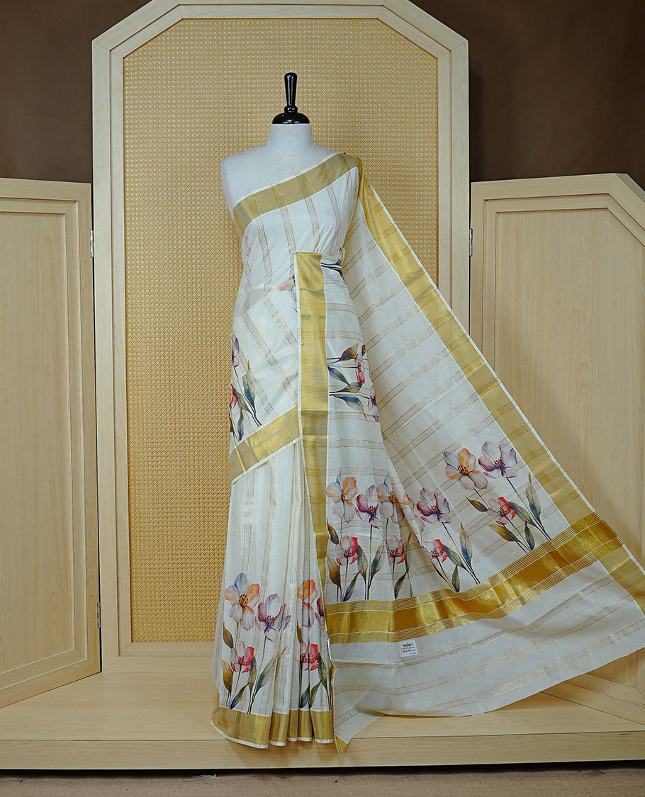 Cream Colour Cotton Kerala Sree Featuring Gold Zari Stripes On Body, Enrich Gold Zari With Floral Printed Border & Pallu, Paired With Matching Blouse Piece.