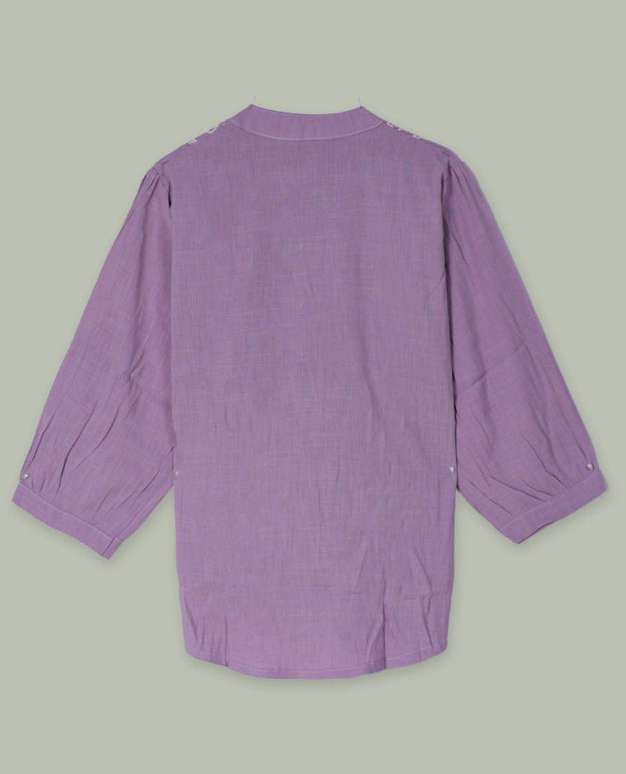 Lilac three-quarter sleeve tunic top with rounded band neckline, white floral embroidered yoke, fabric-covered button placket, and soft pleating below the yoke.
