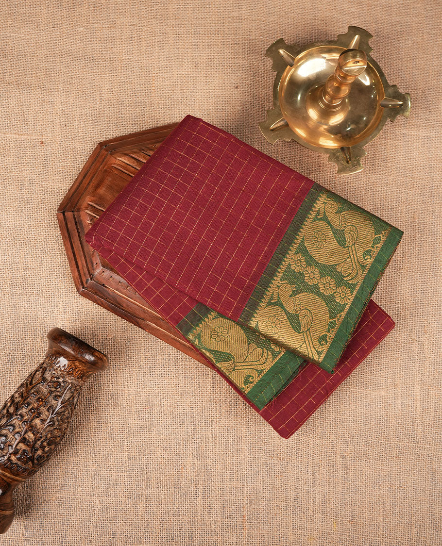 Maroon colour sungudi cotton saree featuring gold zari check pattern across body, contrast green colour with gold zari peacock and floral pattern on border, without blouse piece.