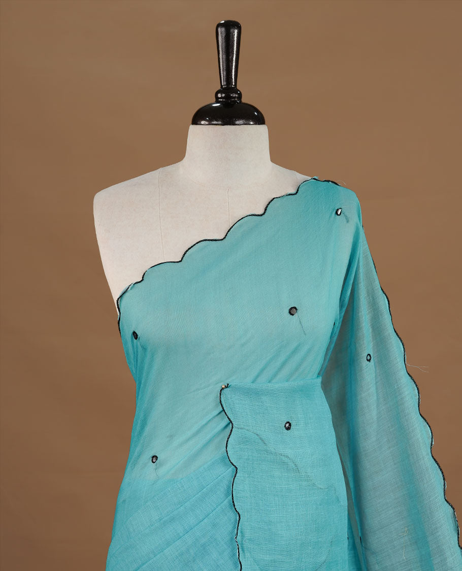 Aqua colour Semi Linen saree featuring mirror work with intricate thread detailing, enhanced by a stylish scallop border. Comes without a blouse piece.