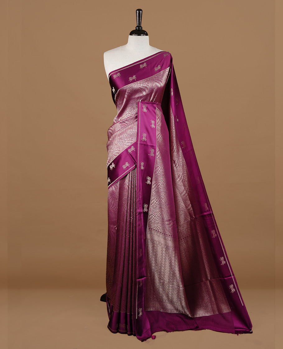 Burgundy colour semi Banaras crepe silk saree featuring an elegant gold zari patterned body, highlighted by a plain border adorned with traditional gold zari cow motifs. Paired with a matching blouse piece.