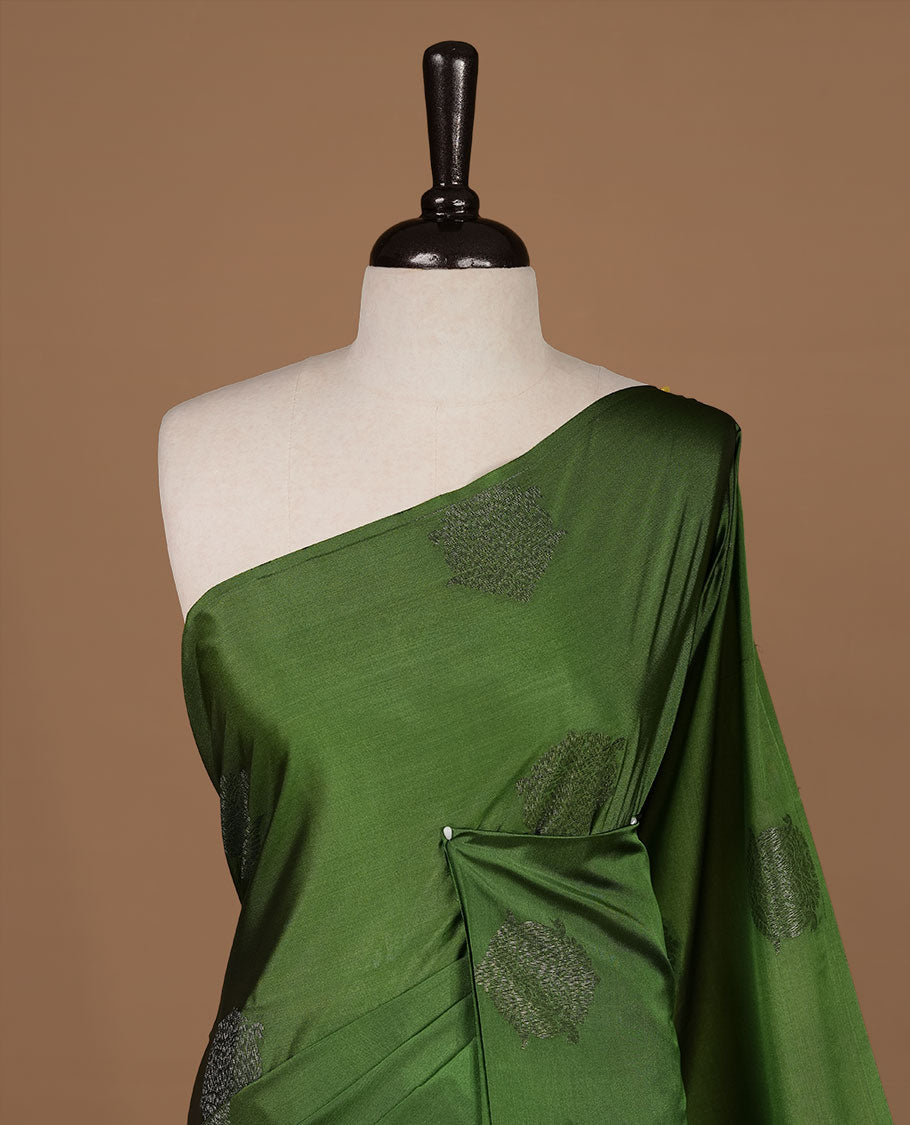 Green colour soft silk saree features a sleek borderless design with intricate antique zari motifs, flowing into a striking contrast chocolate brown pallu and a matching blouse piece.
