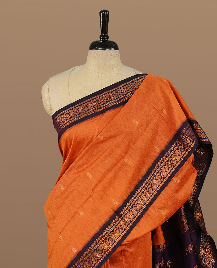 Orange colour kalyani cotton saree featuring Elegant plain body, complemented by Purple colour with Antique zari border, paired with matching blouse piece.