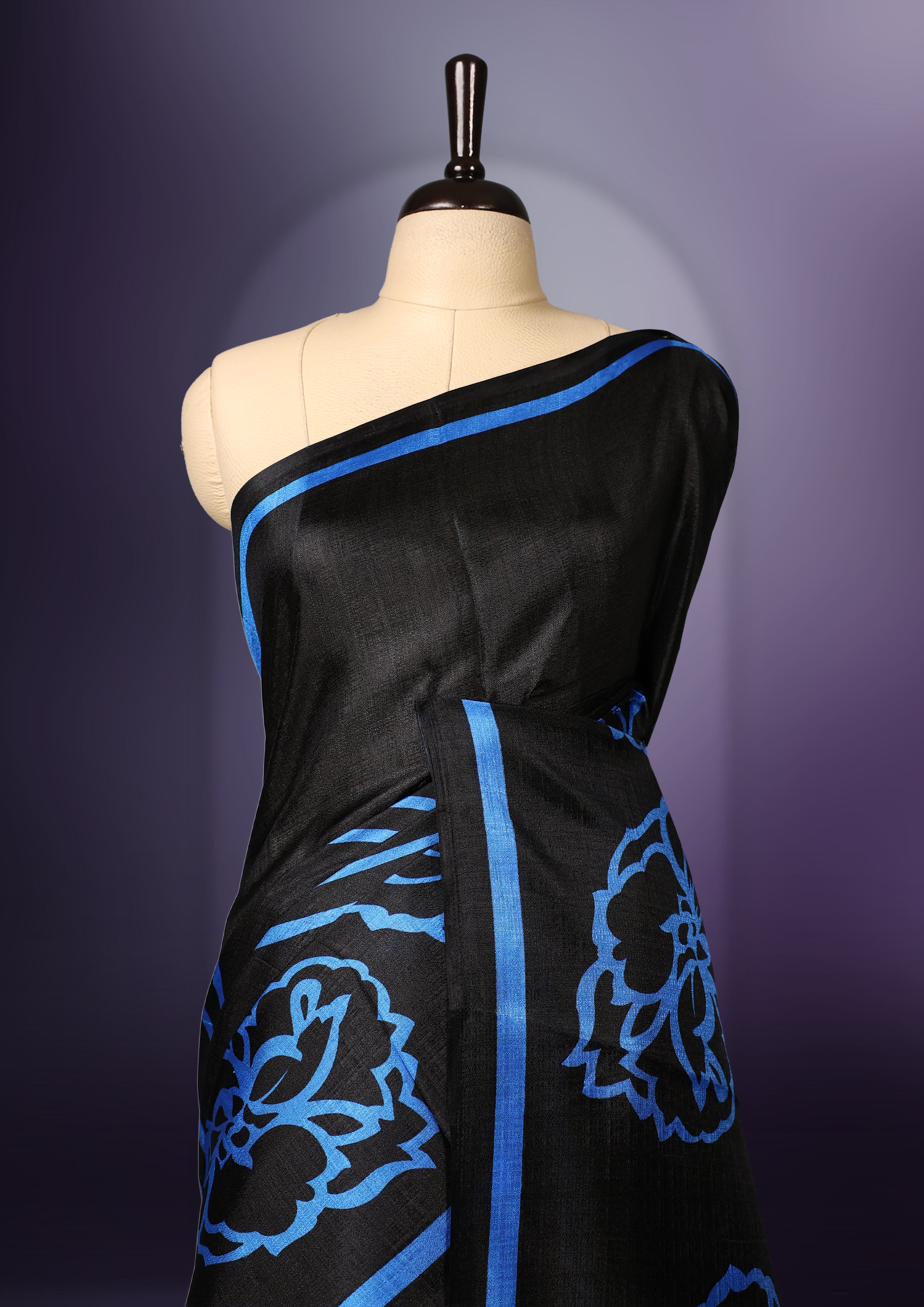 Elegant black colour art silk saree with bold blue floral prints and matching border & Accentuated with a tassel detailed pallu, its perfect for festive evenings or parties. Comes with an unstitched blouse piece.