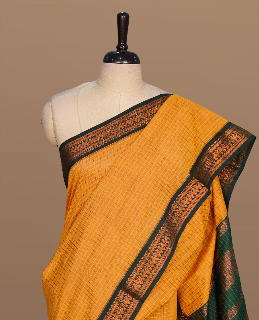 Mustard colour kalyani cotton saree featuring gold zari motifs on body, complemented by contrast green color with copper zari pattern border , paired with matching blouse piece.