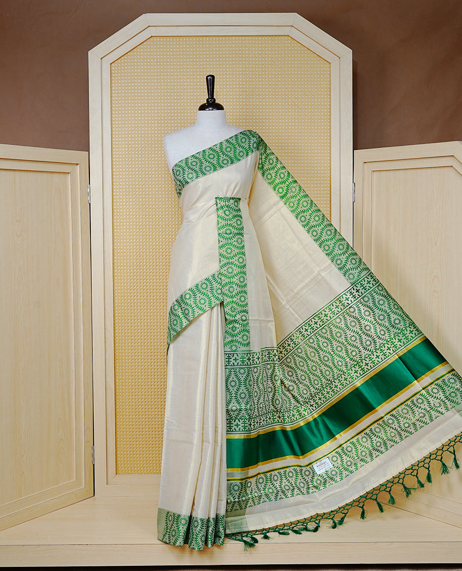 Cream Colour Tissue Kerala Saree Featuring a Plain Body, Enhanced with Green Block Printed Borders, a Green and Gold Zari Pallu, Green Tassels, and a Matching Blouse Piece.