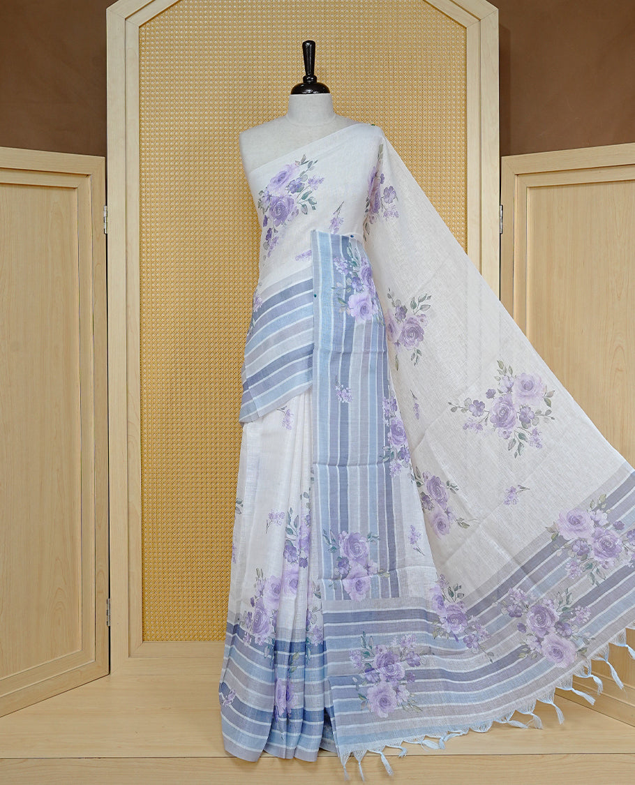 Cream colour semi linen saree featuring Purple colour floral print on body, complemented by contrast Strip pattern border, comes with matching blouse piece.