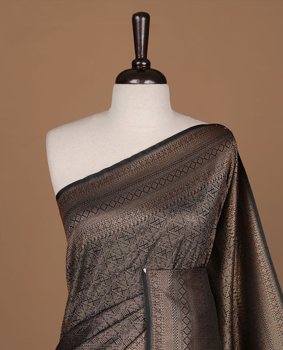Black colour semi banaras katan saree featuring Gold zari Pattern across body, complemented by self colour with zari border, paired with matching blouse piece.