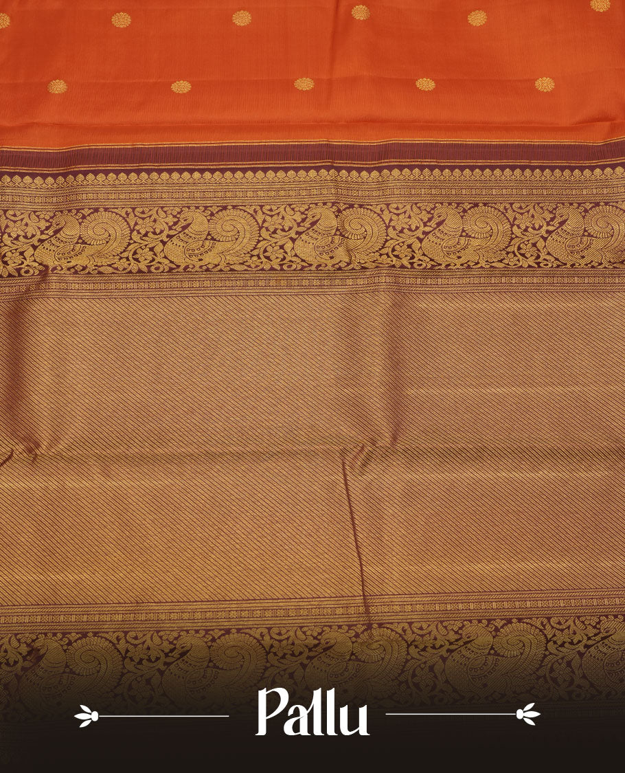 Rust orange colour pure traditional Kancheepuram silk saree adorned with gold zari motifs across the body, featuring elegant contrast Chocolate colour traditional borders, beautifully paired with a matching blouse piece.