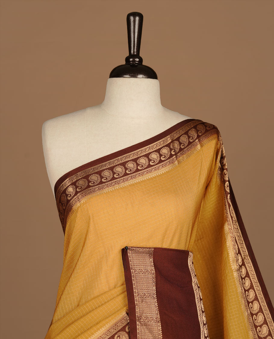 Yellow colour semi georgette saree featuring gold zari check pattern on body, complemented by contrast chocolate colour with zari border, paired with matching blouse piece.