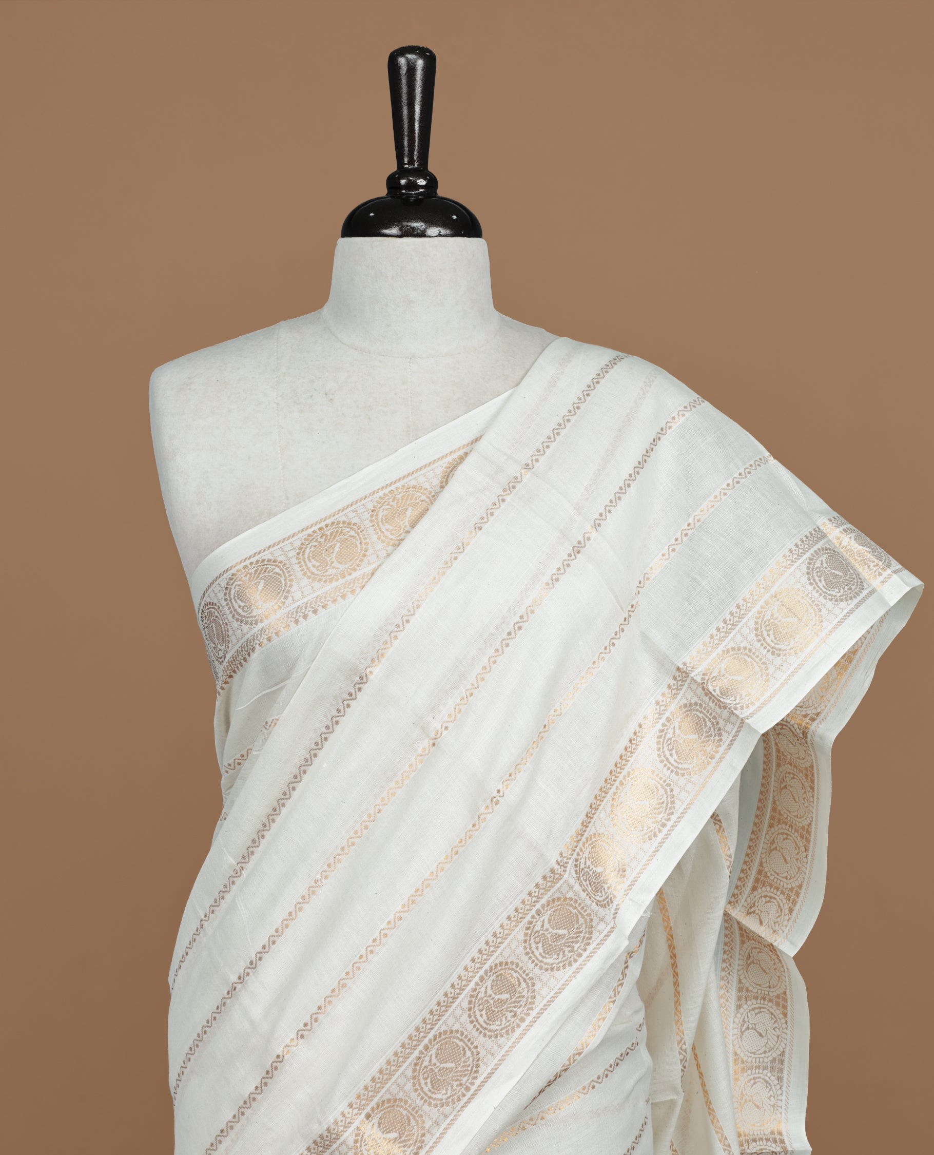 Off white colour Sungudi cotton saree featuring Gold zari Zigzag stripes on body, Gold zari Peacock chakram design on Self colour border, paired with matching blouse piece.