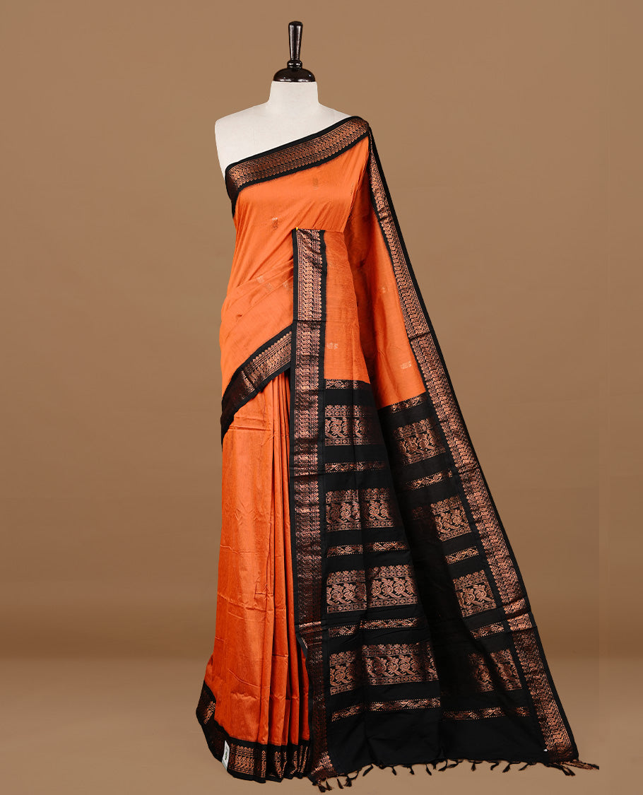 Orange colour kalyani cotton saree featuring gold zari motifs on body, highlighting contrast Black colour with Antique gold zari border, paired with matching blouse piece.