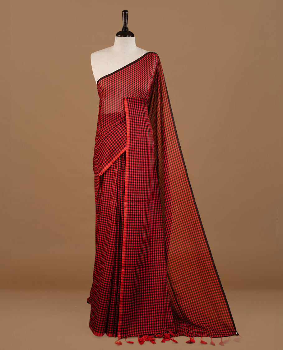 Red and Black colour Mul Cotton saree featuring a classic small check pattern on the body, accented with tassels for added charm. Comes without a blouse piece.