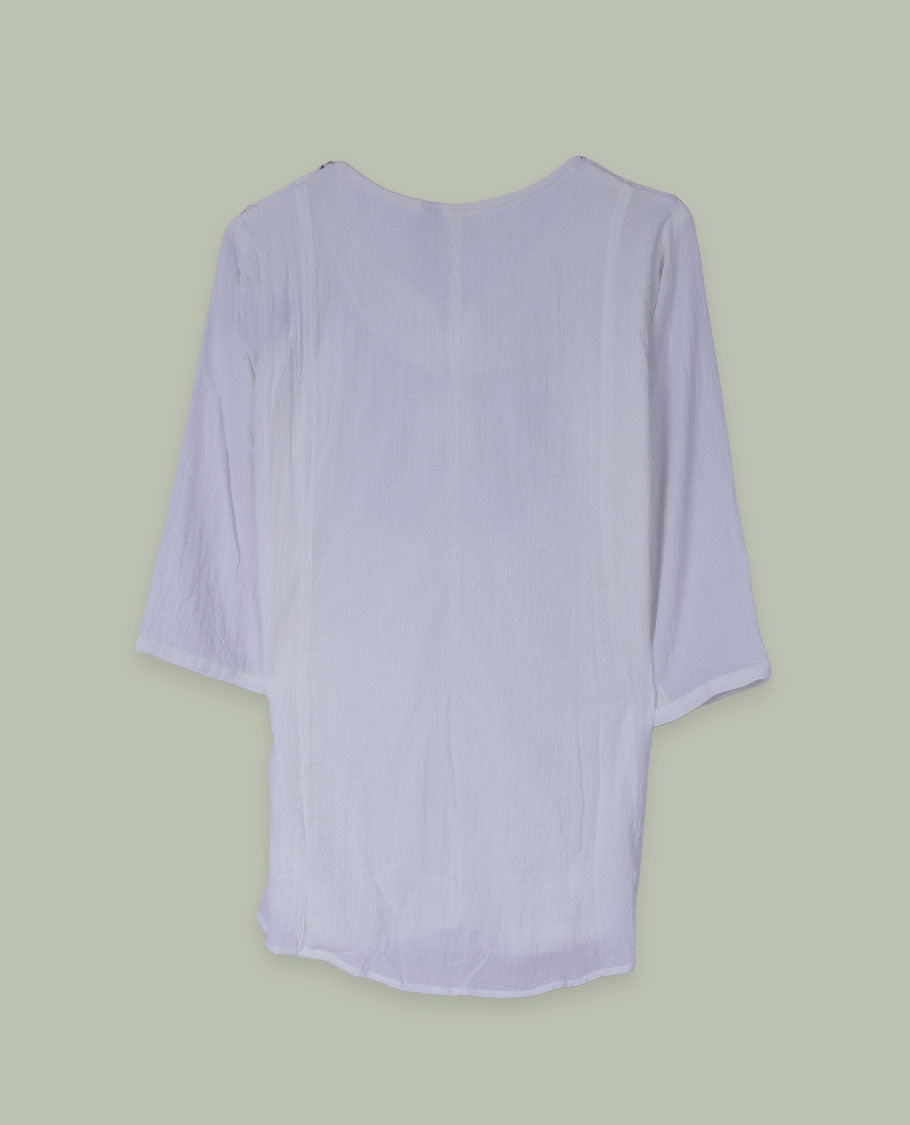 White three-quarter sleeve tunic top with round neckline and front yoke featuring red and green floral embroidery with tie-up detail at the neck.