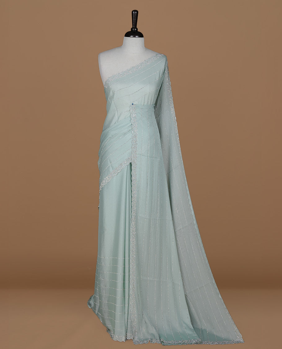 Light blue colour designer saree featuring white stone stripes on body, highlighting white stone with scalp border, paired with matching blouse piece.