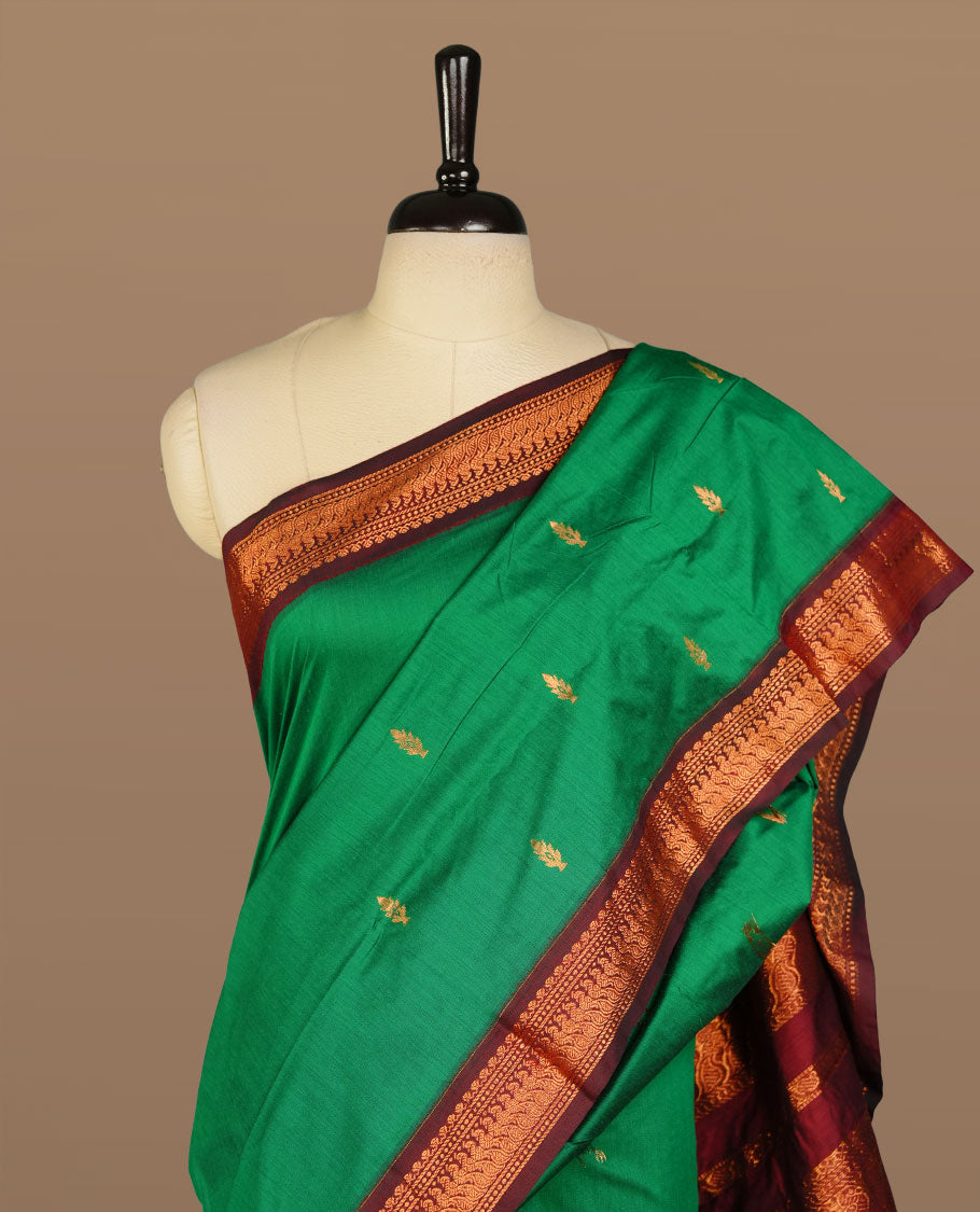 Green colour kalyani cotton saree featuring antique zari motifs on body, complemented by Maroon colour with Antique zari border, paired with matching blouse piece.