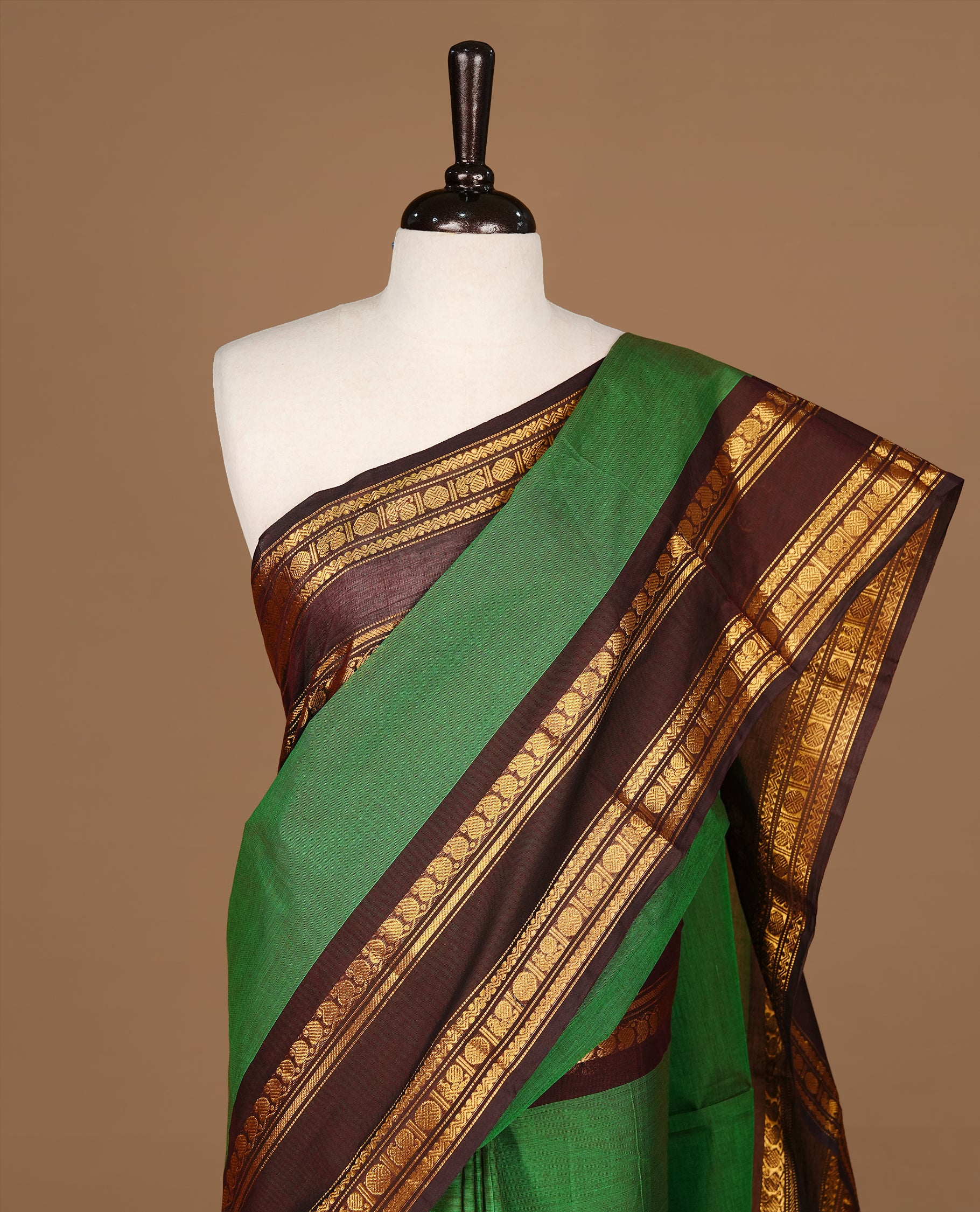 Green colour Chettinad cotton saree featuring Elegant plain body, complemented by contrast Chocolate Brown colour with gold zari border, paired with matching blouse piece.