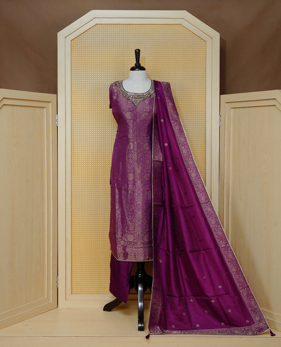 Royal purple churidar set with an ornate embellished round neckline, floral zari pattern, paired with a matching dupatta featuring zari butis and an intricate border & solid pants.