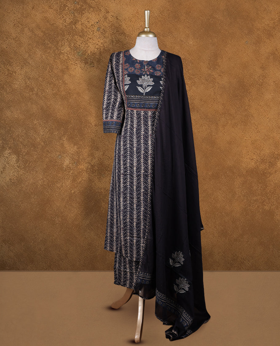 Charcoal black colour churidar set featuring round neckline, three‑fourth sleeves, and ethnic floral printed yoke and body, paired with a solid black dupatta adorned with subtle floral motifs.