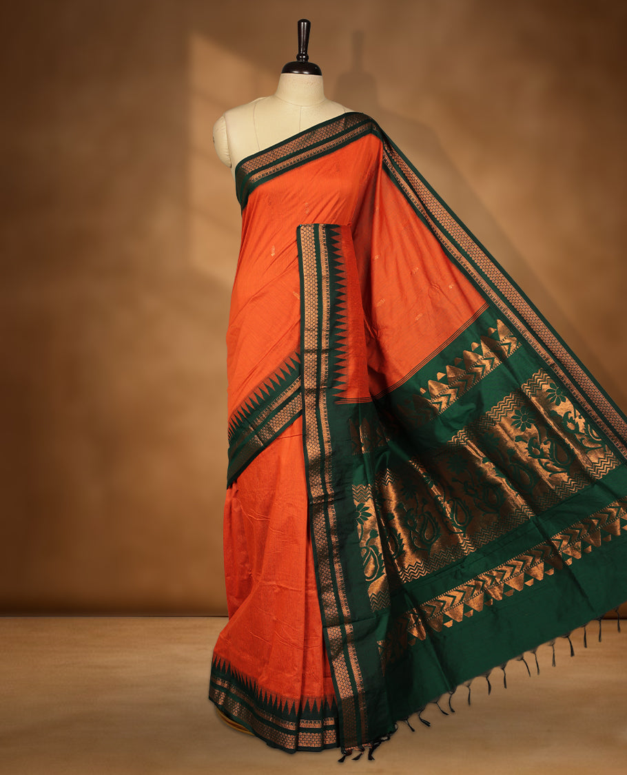 Orange colour kalyani cotton saree featuring Antique zari motifs on body, contrast green colour border with geometric antique zari pattern, paired with matching blouse piece.