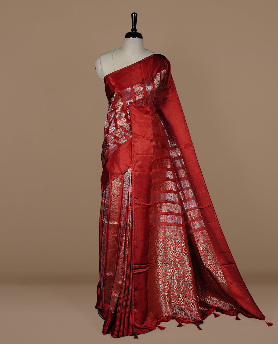 Red colour banaras crepe saree featuring gold & silver zari design stripes on body, complemented by self colour border, paired with matching blouse piece.