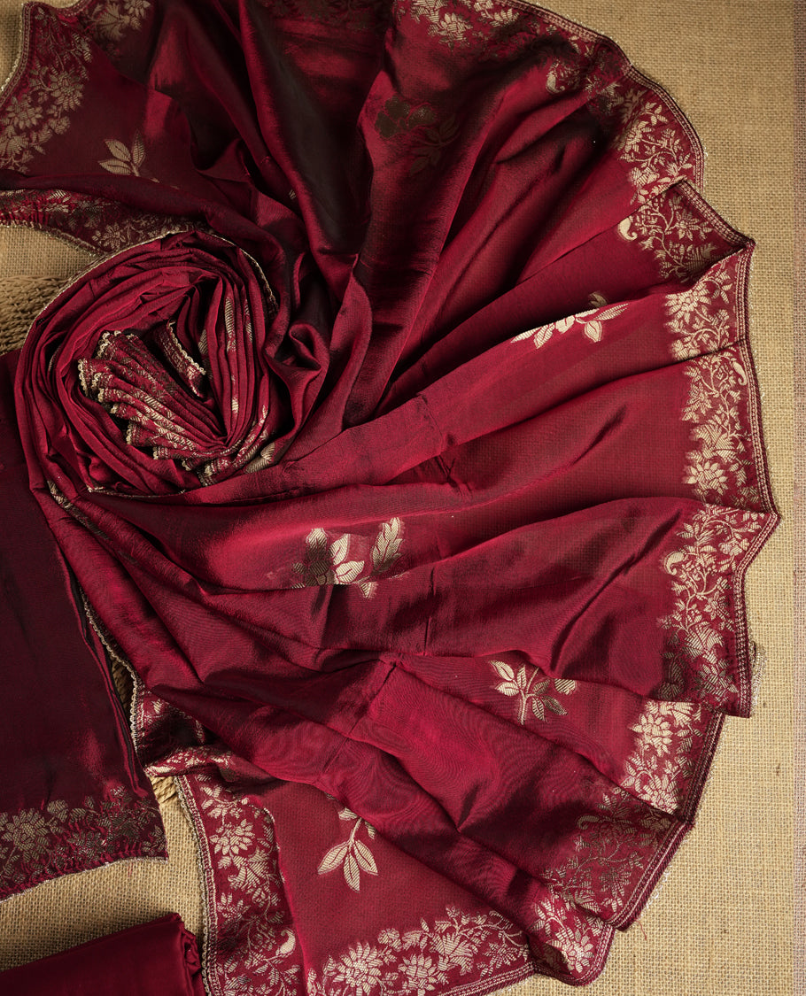 Elegant maroon colour suit material adorned with exquisite zari floral weaving, exuding regal charm & paired with a beautifully bordered dupatta and a matching plain bottom.