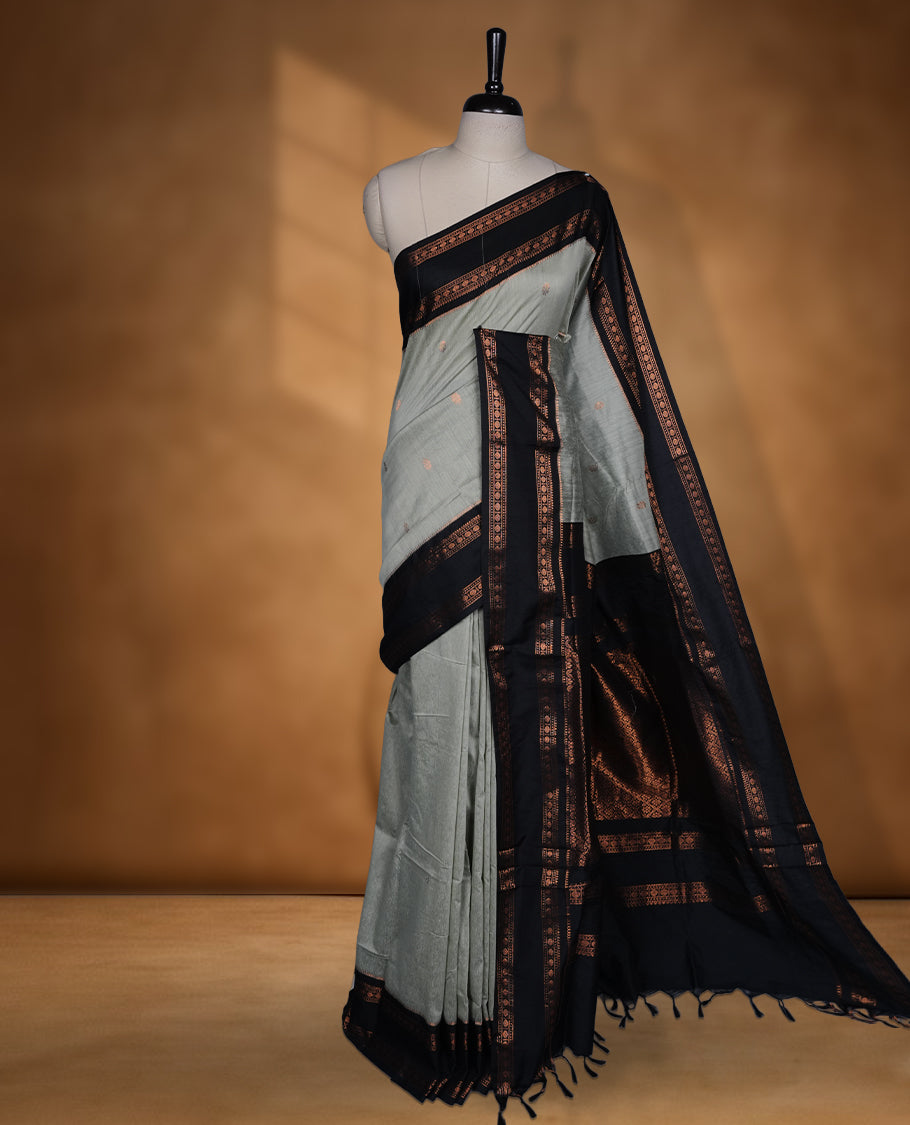 Grey colour Kalyani cotton saree featuring a plain elegant body, complemented by a black zari border and traditional woven pallu, paired with a matching blouse.