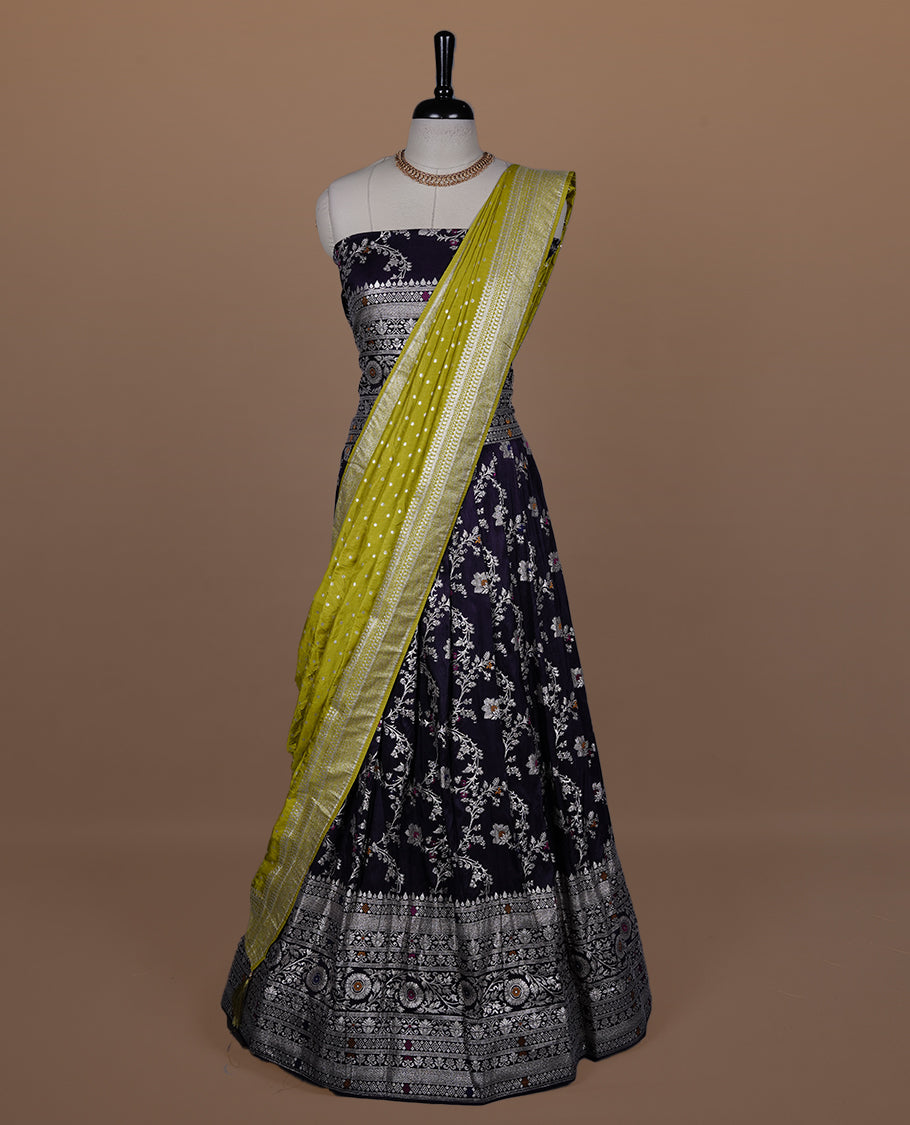 Deep purple colour semi banaras semi stitched dhavani set featuring gold zari floral kodi motifs and traditional border, unstitched matching blouse piece and contrast Olive colour Duptta with gold zari border.