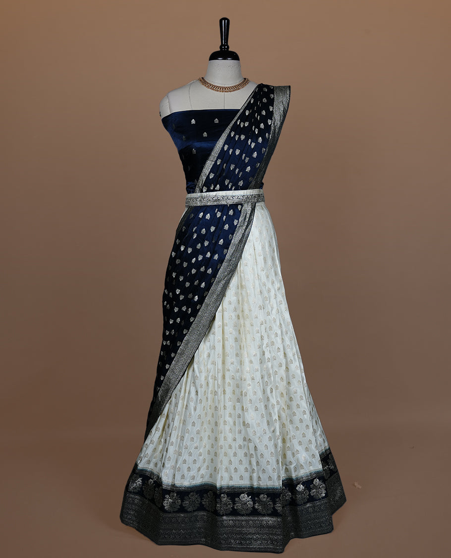Off white semi banaras semi stitched dhavani set featuring gold zari motifs and contrast Teal colour and traditional border, unstitched gold zari blouse piece and matching Duptta.