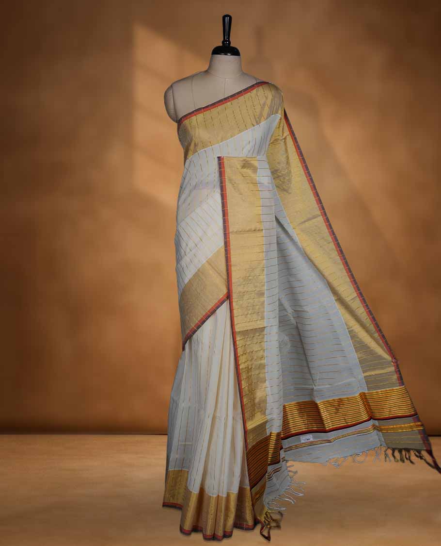 Off white Cotton Kerala saree with a striped body, wide golden zari border with orange and brown accents, and traditional pallu, paired with a matching blouse.