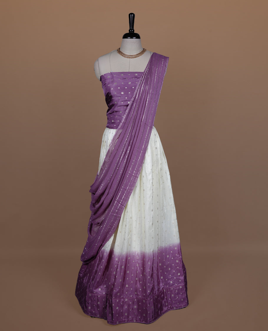 Off white semi banaras semi stitched dhavani set featuring gold zari motifs and contrast Purple colour border, unstitched gold zari blouse piece and matching Duptta with gold zari stripes.