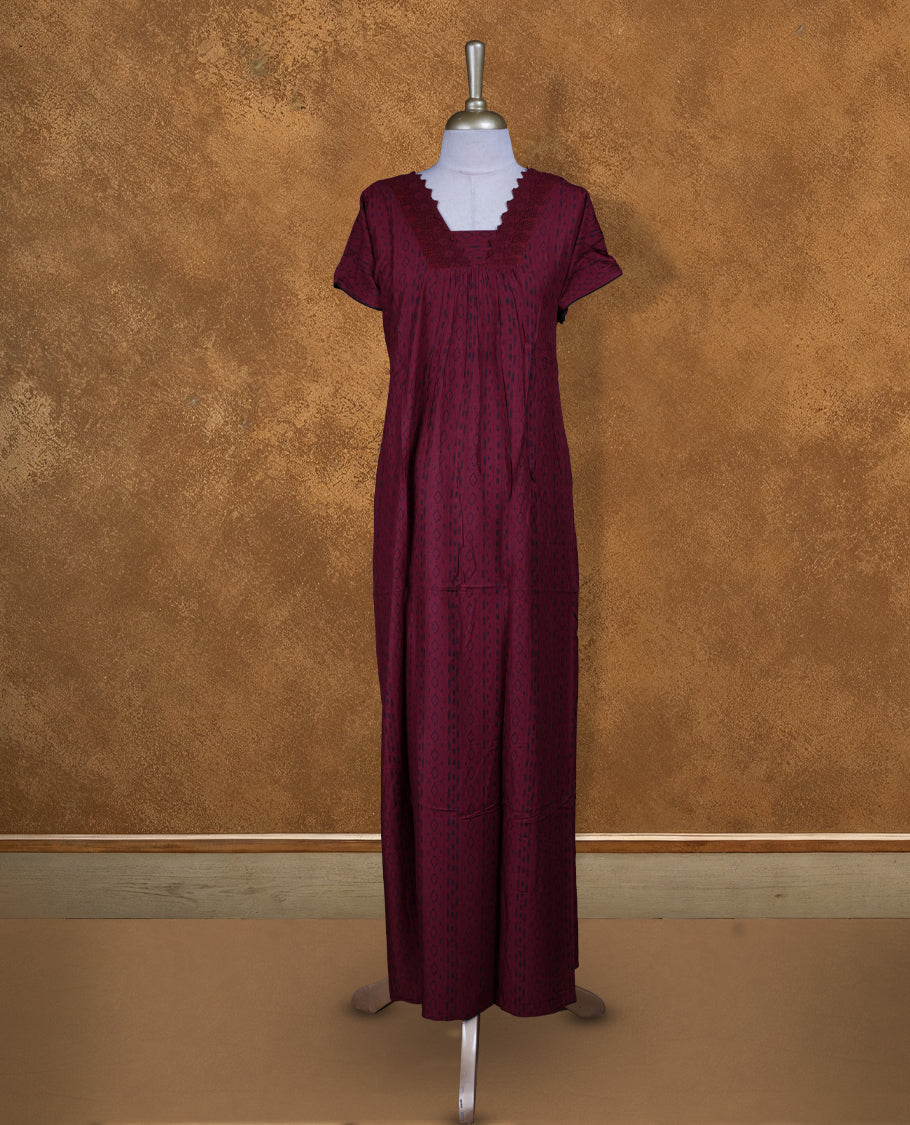 Dark red colour NStyle nighty featuring black patterns, a V-neckline with thread lace detailing, short sleeves, and a full ankle-length design.