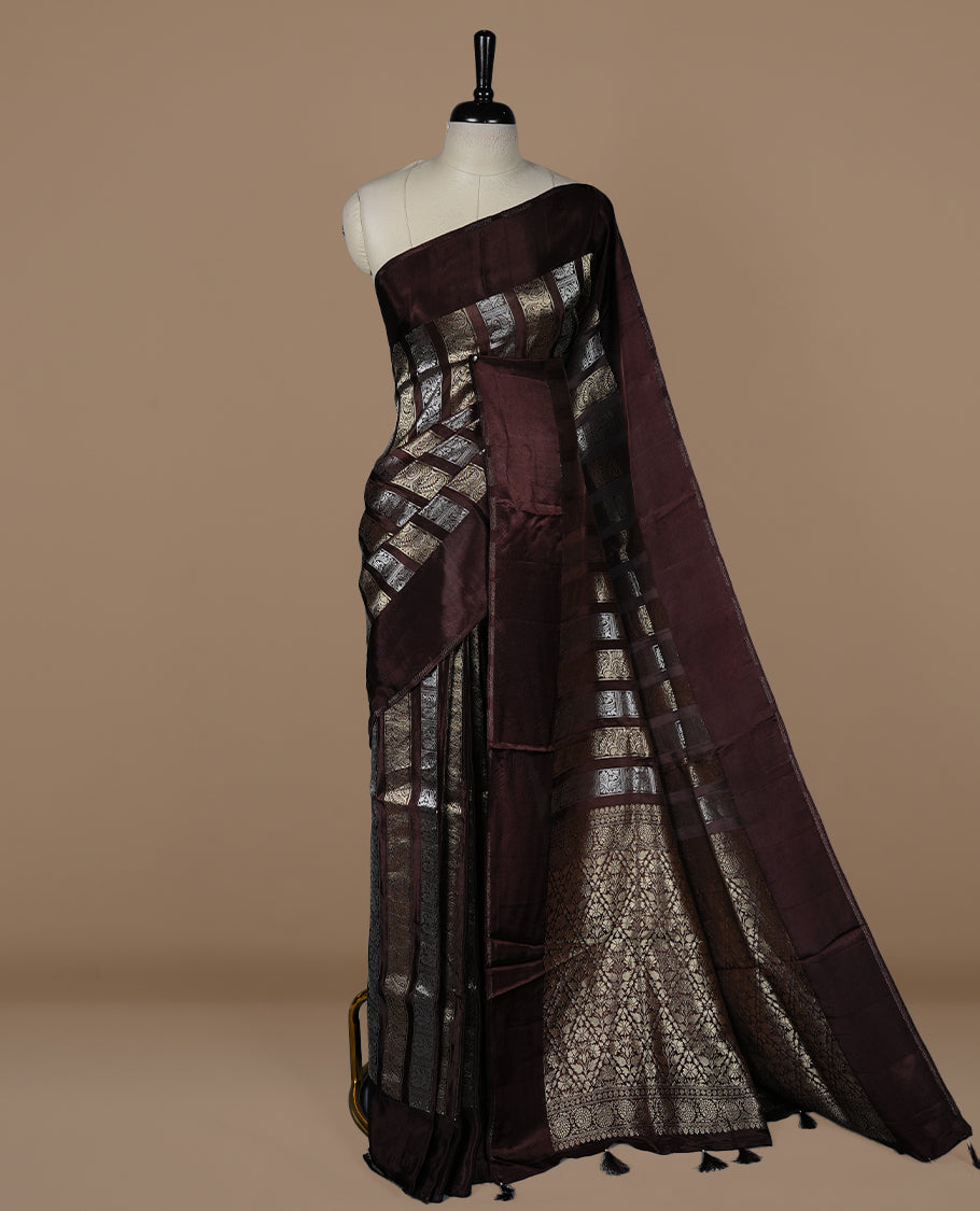 Chocolate colour banaras crepe saree featuring gold & silver zari design stripes on body, complemented by self colour border, paired with matching blouse piece.
