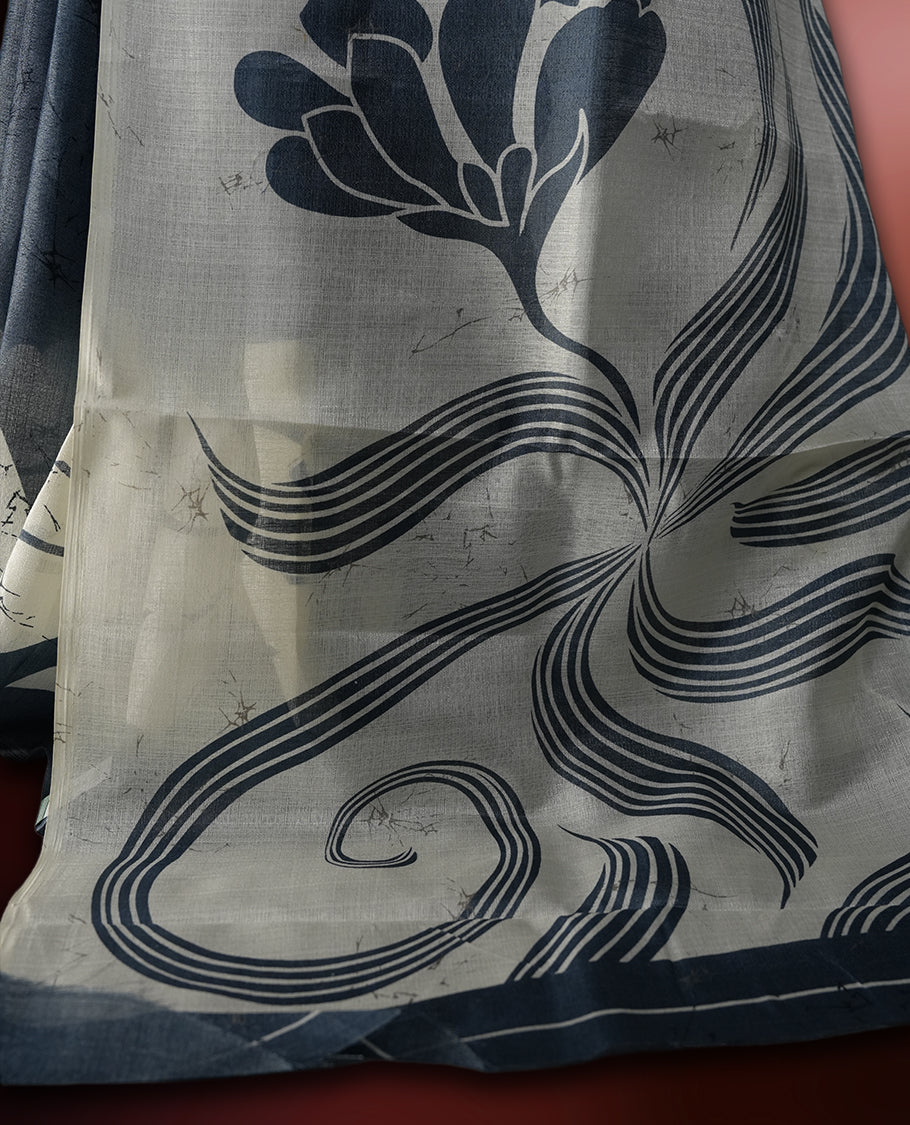 Grey and off white colour saree featuring bold floral and abstract prints across the body and pallu, offering a perfect blend of elegance and modern style, paired with a matching blouse piece.