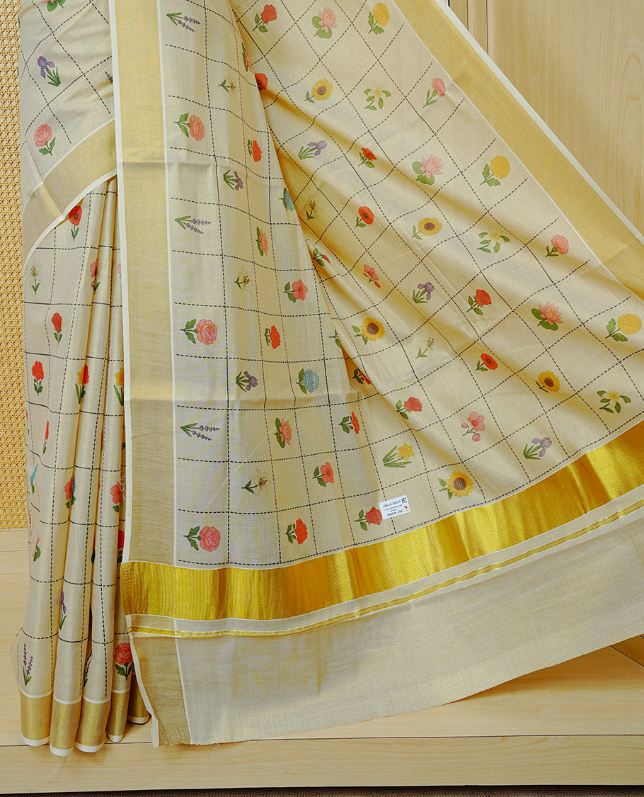 Cream Colour Tissue Kerala Saree Featuring Multicolour Floral Motifs In A Checked Pattern Across The Body, Enhanced With A Gold Zari Border And A Traditional Gold Zari Pallu, Finished With A Matching Blouse Piece
