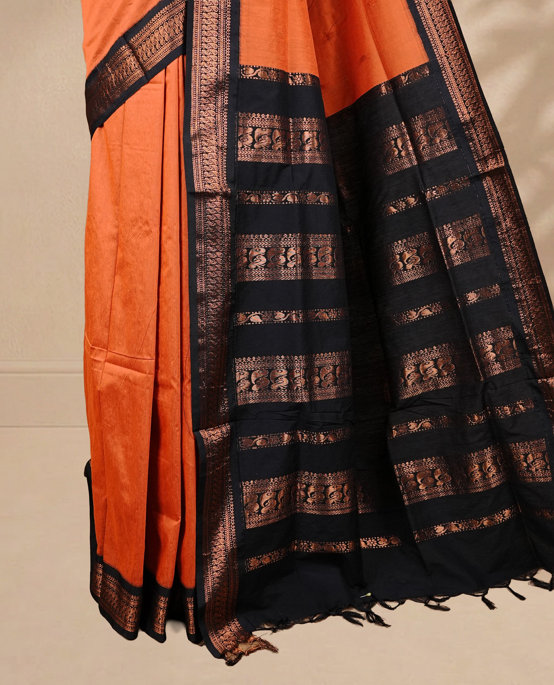 Orange colour kalyani cotton saree featuring antique zari motifs on body, complemented by Black colour with Antique zari border, paired with matching blouse piece.