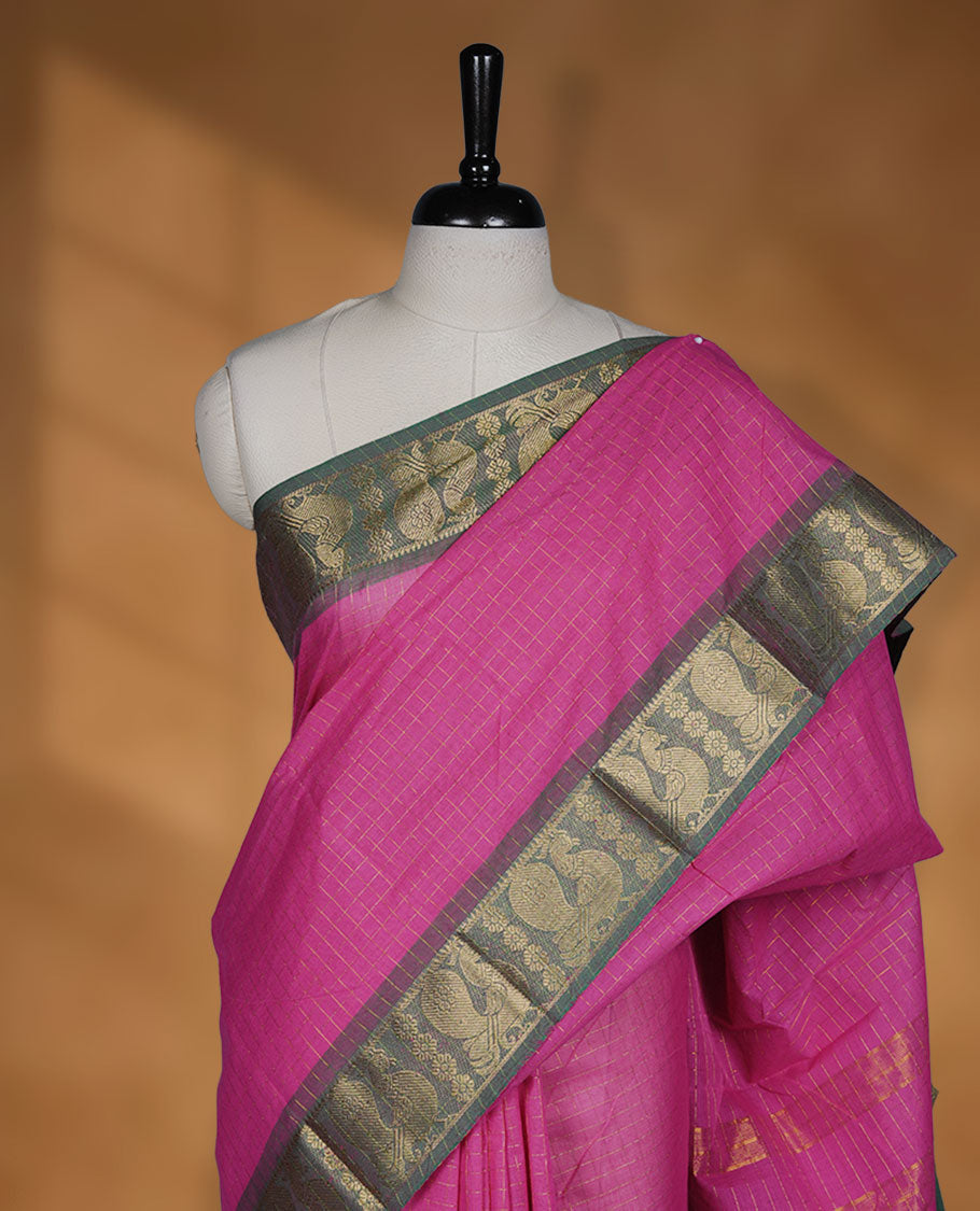 Magenta colour sungudi cotton saree featuring gold zari check pattern across body, contrast green colour with gold zari peacock and floral pattern on border, without blouse piece.