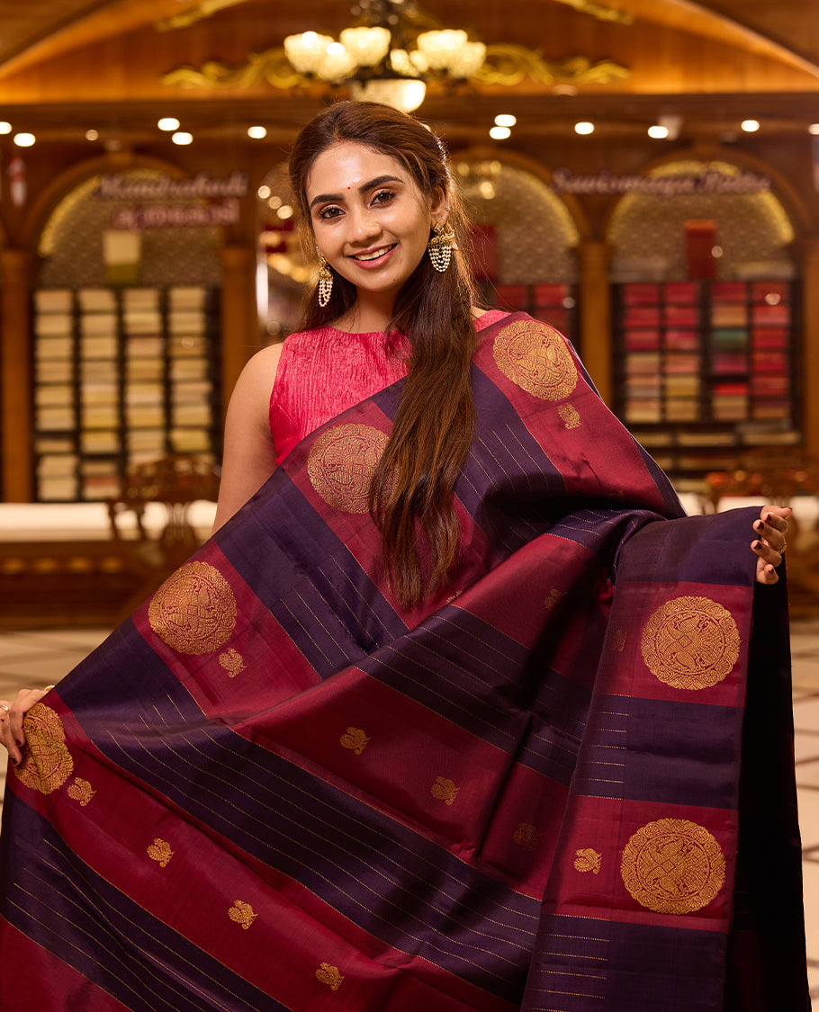 Graceful maroon and deep indigo colour kancheepuram silk saree adorned with classic gold zari polka motifs and elegant horizontal weaving, finished with a striking pallu and perfectly complemented by a blouse