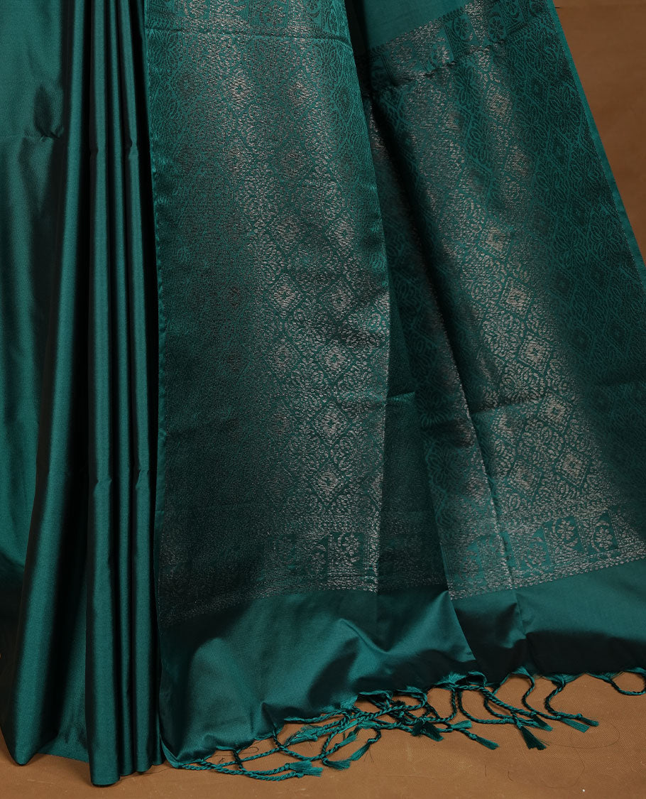 Teal green soft silk saree features a sleek borderless design with intricate antique zari motifs, flowing into a seamless self colored pallu and a matching blouse piece.