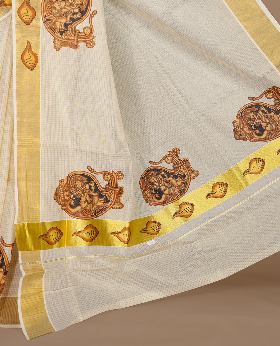 Off white color kerala cotton saree featuring gold zari check on body, complemented by, gold zari with krishna printed border, paired with matching blouse piece.