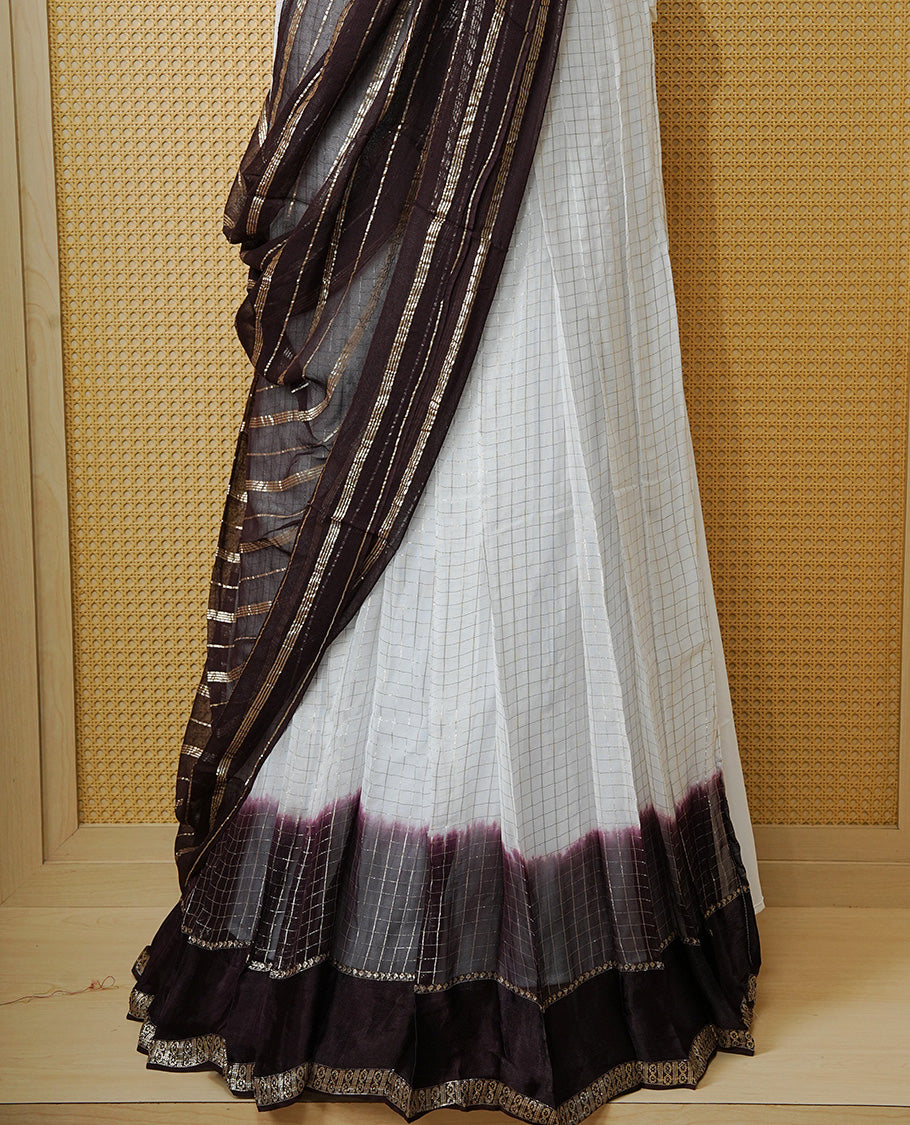 Off white colour Semi stitched dhavani set featuring Gold zari check pattern with contrast Chocolate colour border skirt, paired with matching blouse & dupatta.