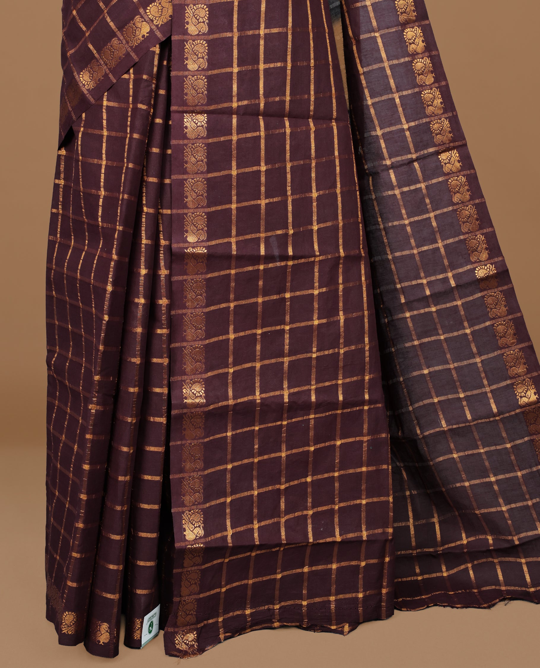 Dark chocolate colour Sungudi cotton saree featuring Gold zari Check pattern on body, Gold zari Peacock design on Self colour border, paired with matching blouse piece.