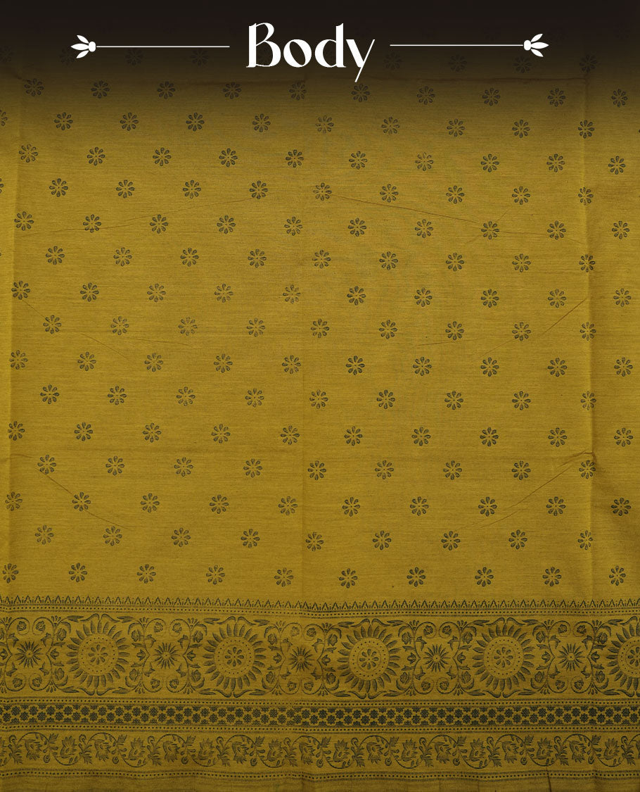 Dark Mustard colour poly cotton saree with black floral butti motifs on the body, paired with a matching pallu featuring black ornate floral jaal and stripes on the border, and a coordinated all‑over black paisley printed blouse piece.