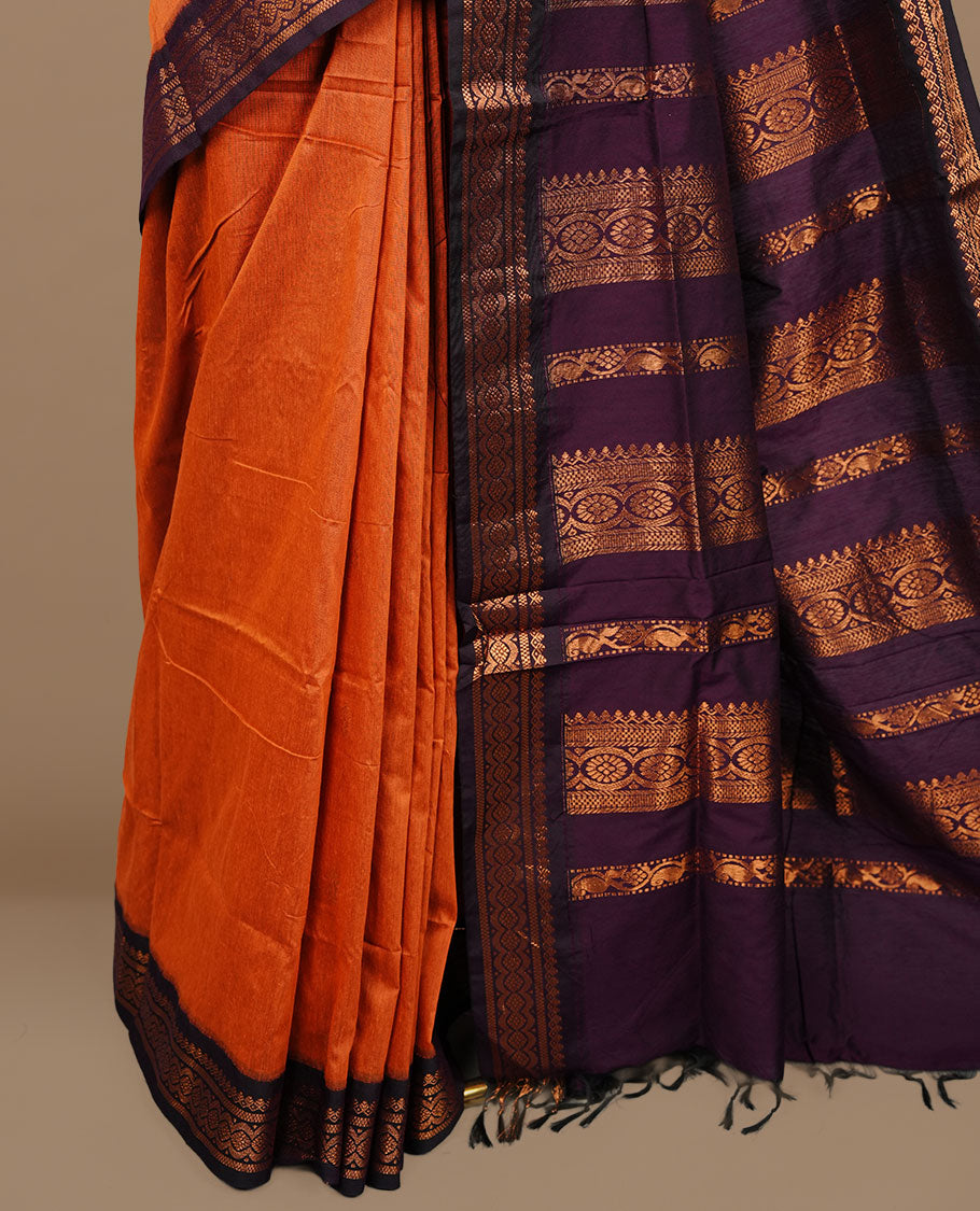 Orange colour kalyani cotton saree featuring Elegant plain body, complemented by Purple colour with Antique zari border, paired with matching blouse piece.