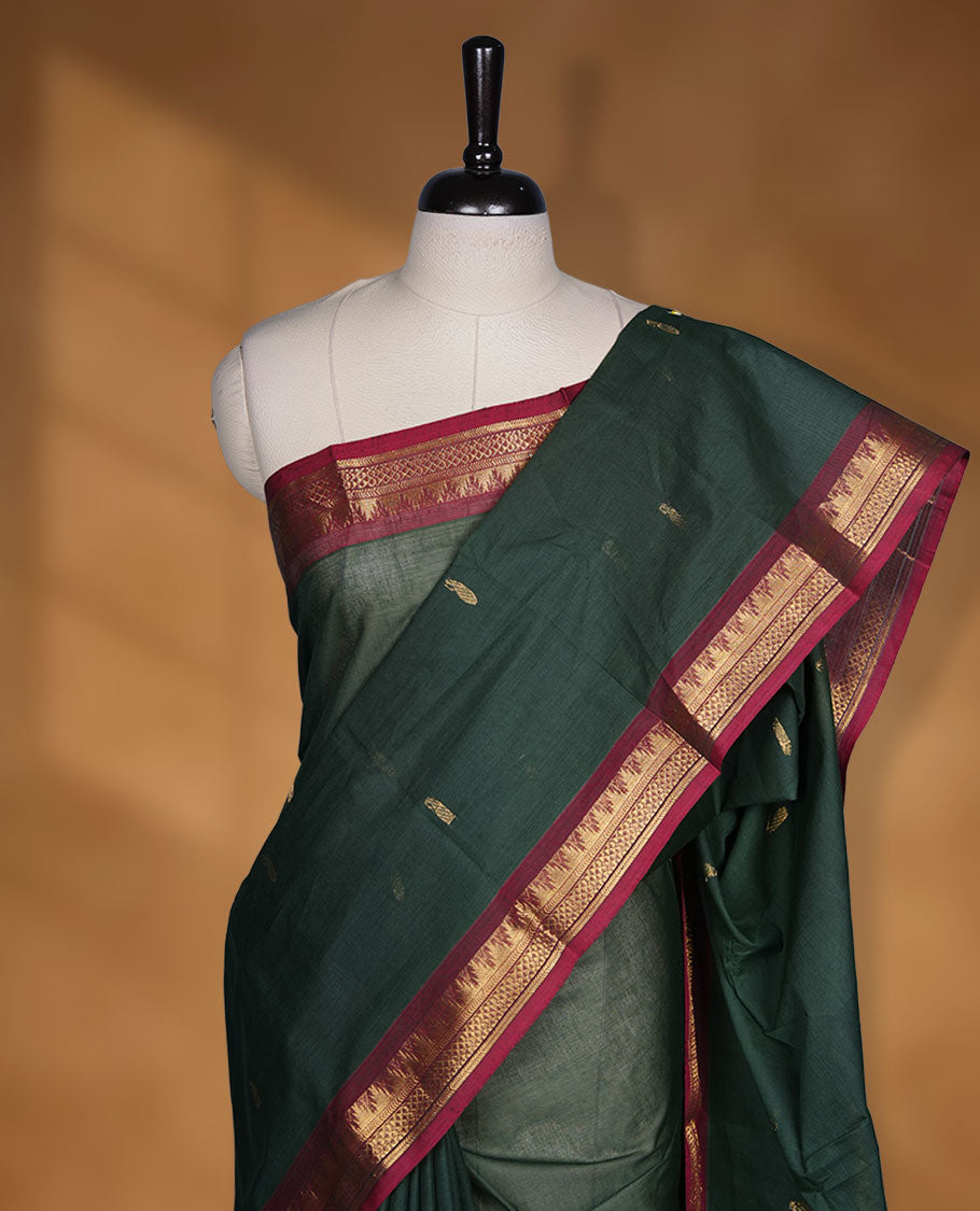 Dark green colour chettinad cotton saree featuring gold zari motifs on body, contrast Red colour with traditional gold zari border paired with matching blouse.