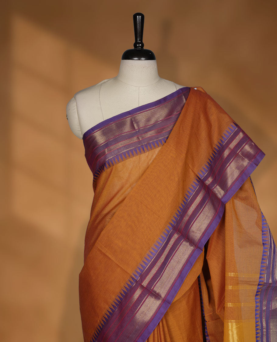 Brown colour chettinad cotton saree featuring elegant plain body highlighting contrast indigo colour with gold zari traditional border, pallu and paired with matching blouse piece.