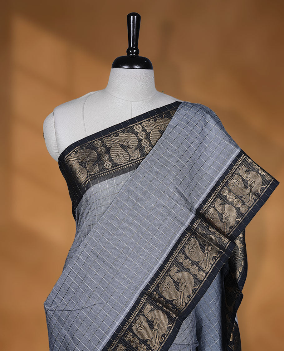 Grey colour sungudi cotton saree featuring gold zari check pattern across body, contrast Black colour with gold zari peacock and floral pattern on border, without blouse piece.